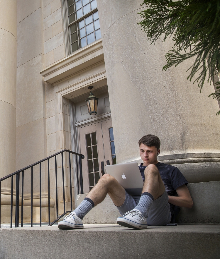 student with laptop on Chambers pillars by steps 