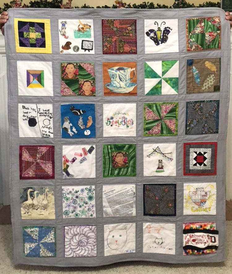 Quilt of Patches from Community being held up