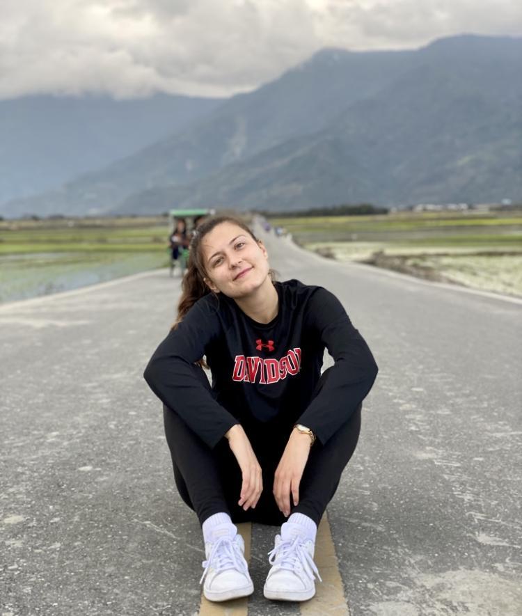 Eldina Kucevic sitting on an empty road with mountains behind her