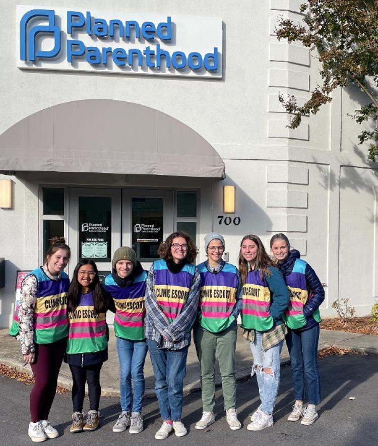 students standing in front of Planned Parenthood wearing "clinic escort" shirts