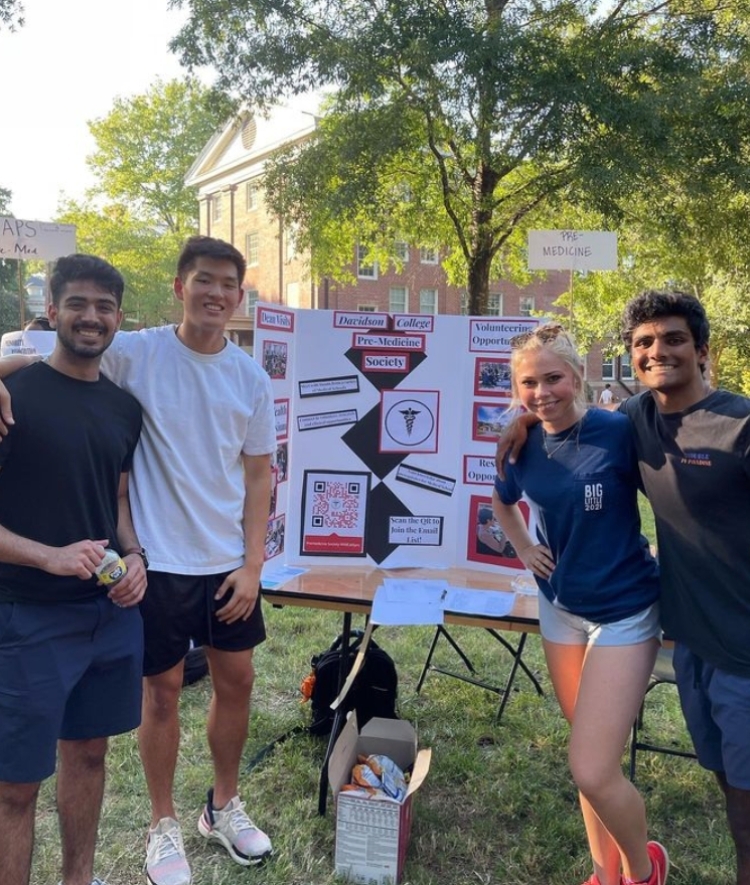 students outside at table with "premed society" sign behind them