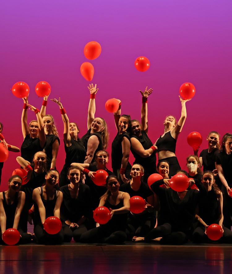 dancers posing with red balloons