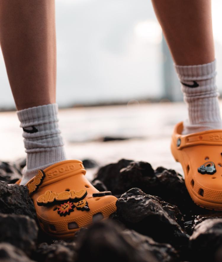 Orange Crocs with white socks climbing on rocks