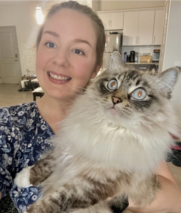 A white woman holding a cat and smiling