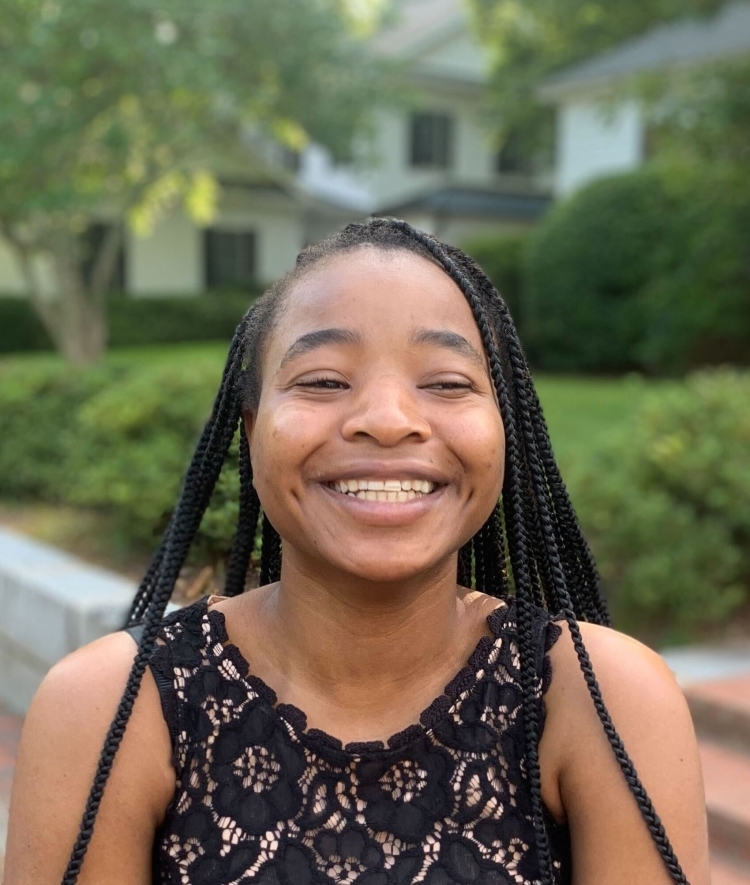 A young Black woman smiles and wears a black lace dress