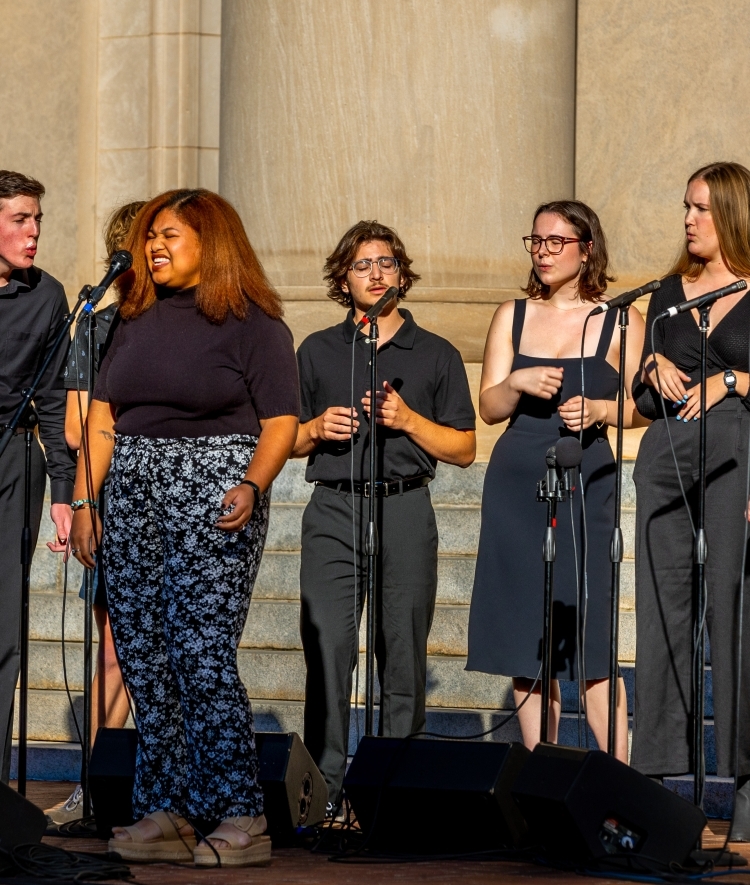 a group of students in black outfits singing