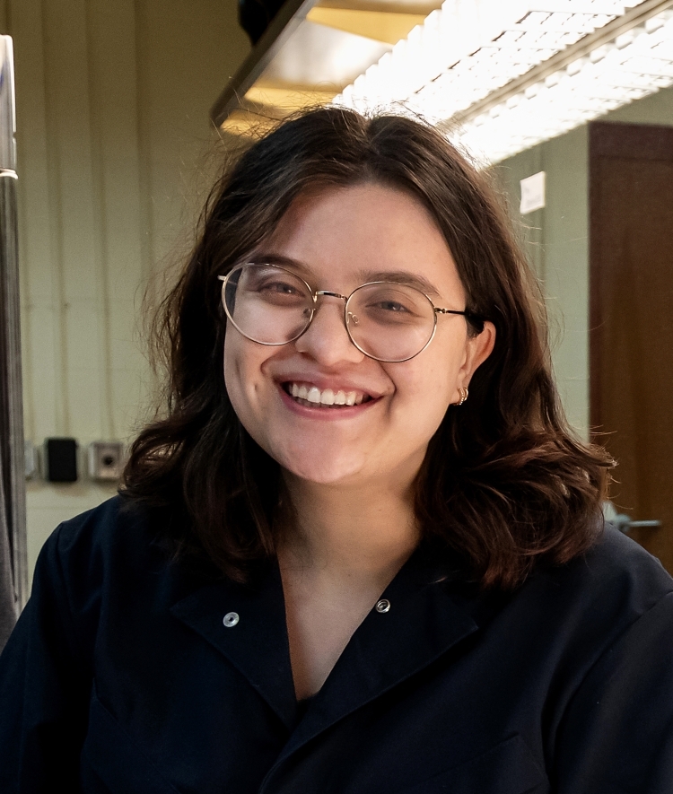 a young woman with dark hair wearing glasses and smiling