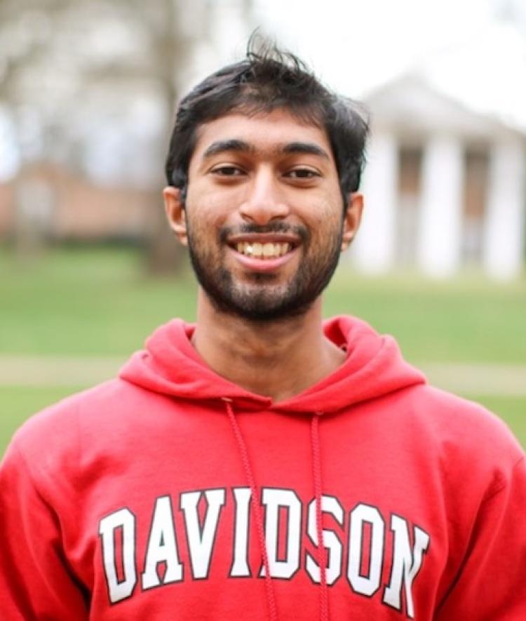 a young man wearing a red Davidson sweatshirt and smiling