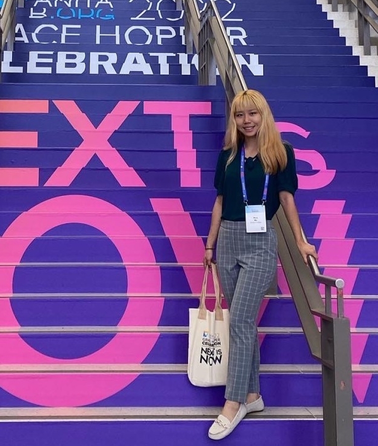 a young woman wearing dress clothes and standing on a colorful set of stairs