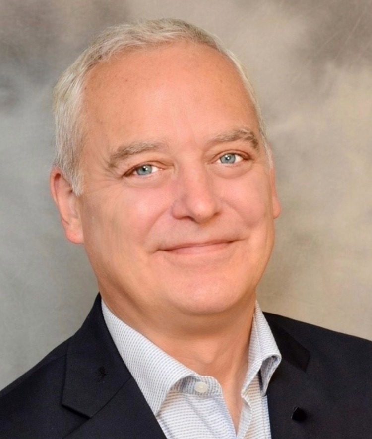 an older white man with white hair wearing a collared shirt and jacket