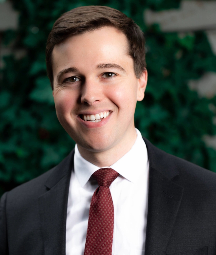 a young white man wearing a suit and tie while smiling