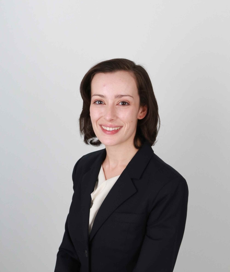 a young white woman wearing a white top and black blazer