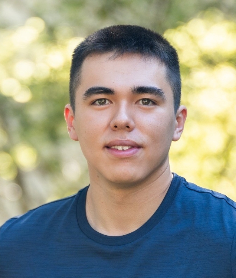 a young man with dark brown hair wearing a navy t shirt