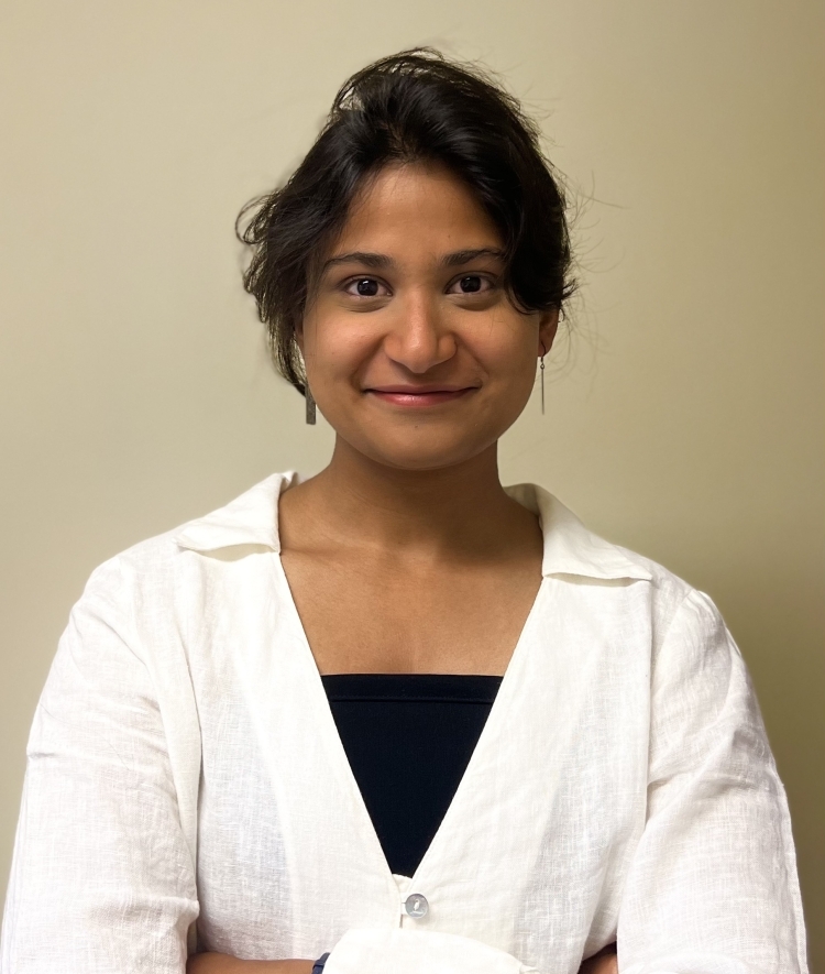 a young Indian woman wearing a white top with her arms crossed