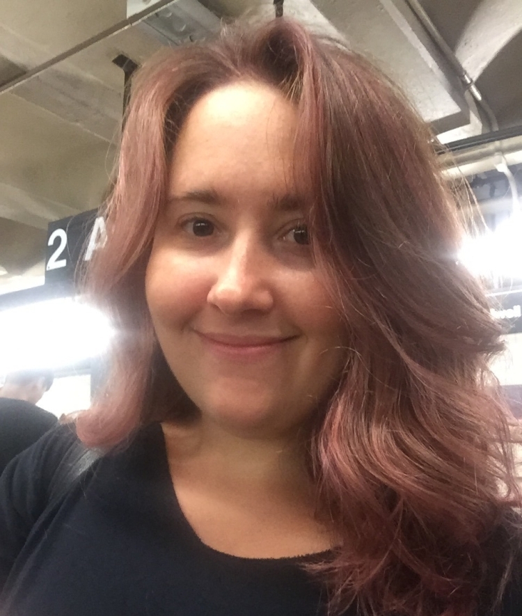 a young white woman with red brown hair smiling and wearing a black top