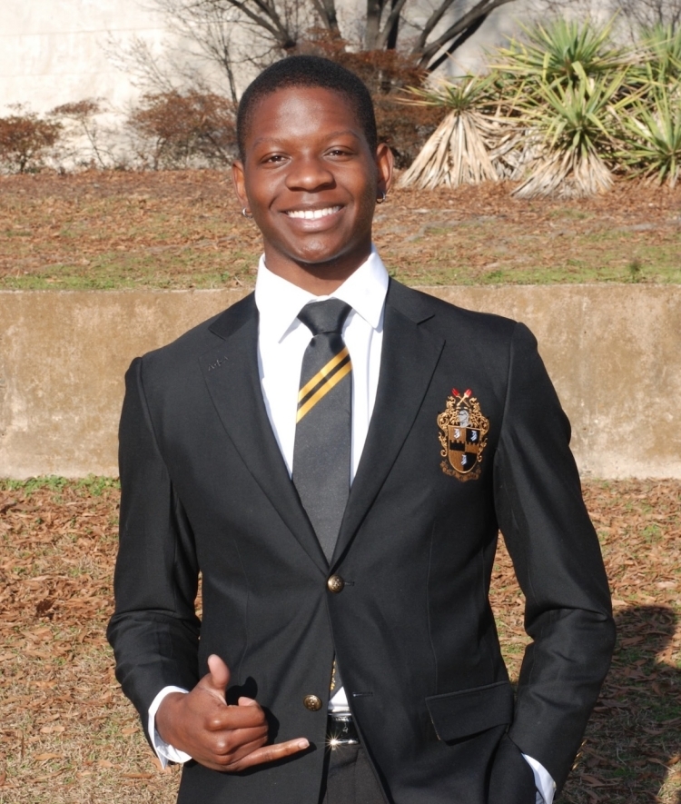 a young Black man wearing a suit and tie while smiling