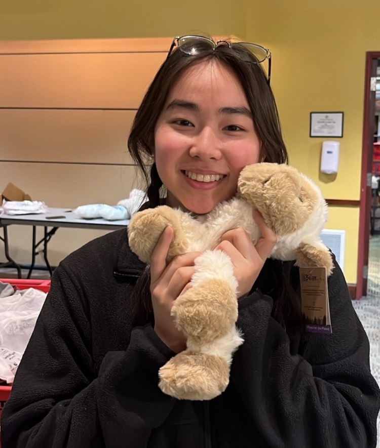 a young woman holds a sheep stuffed animal