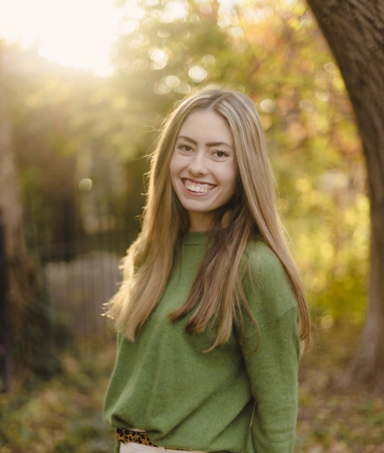 a young white woman standing in the woods wearing a green top