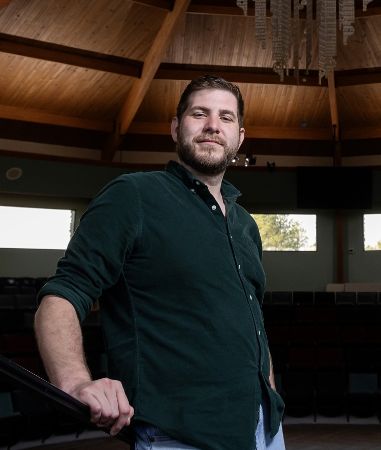 a young man stands in a Catawba space holding a railing and smiling