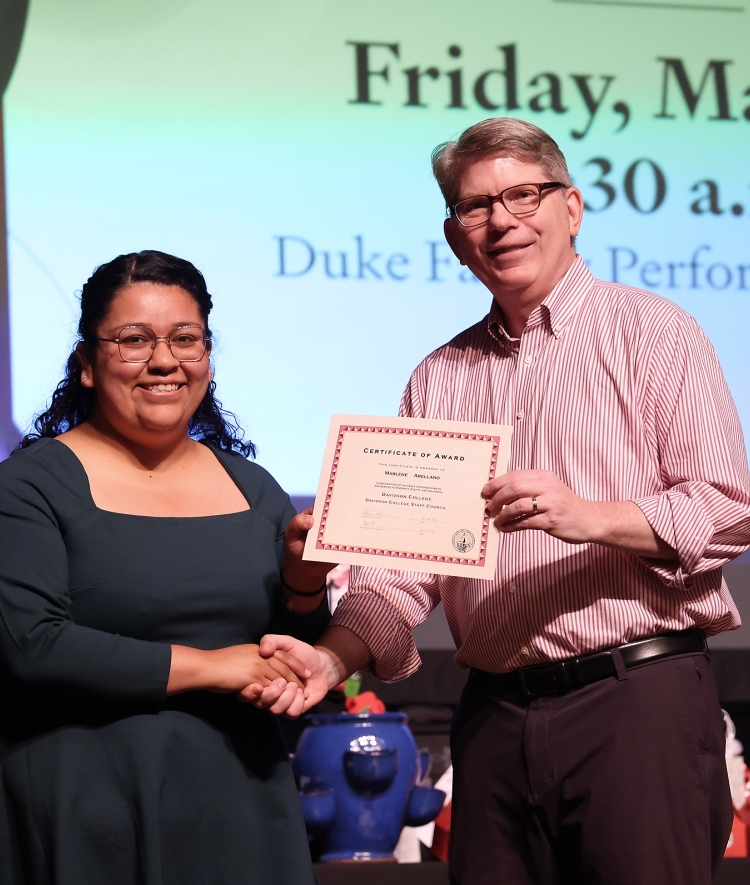 a young woman accepts an award from an older white man