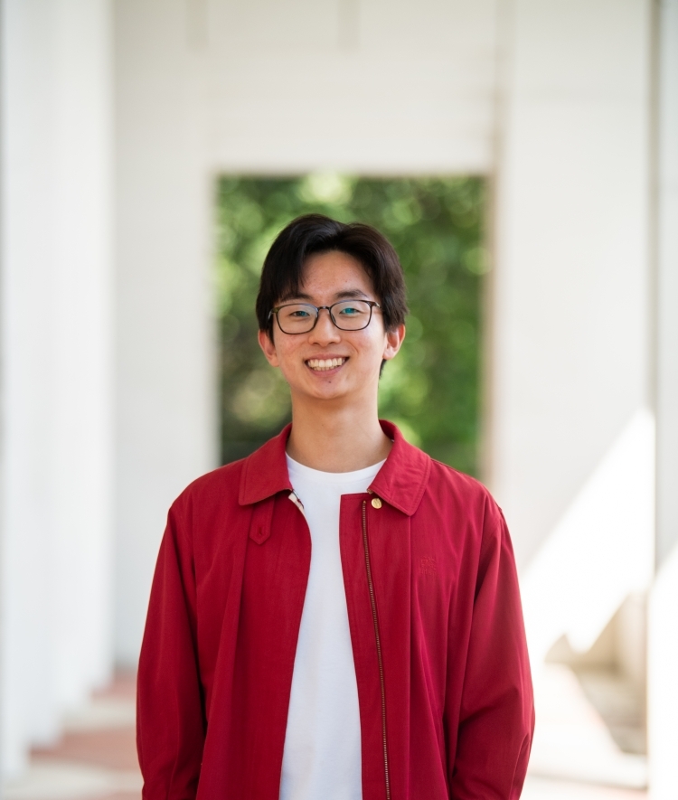 a young Asian man wearing a white t-shirt and red top with glasses