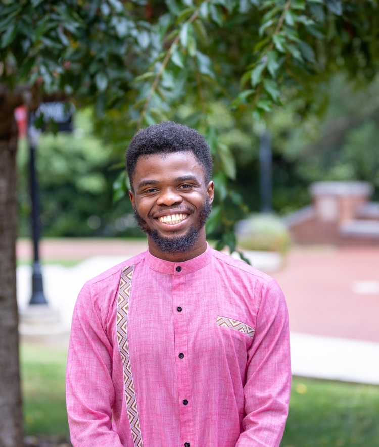 a young Black man wearing pink top