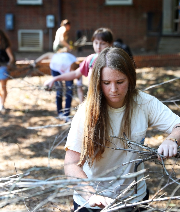 a young woman carries branches