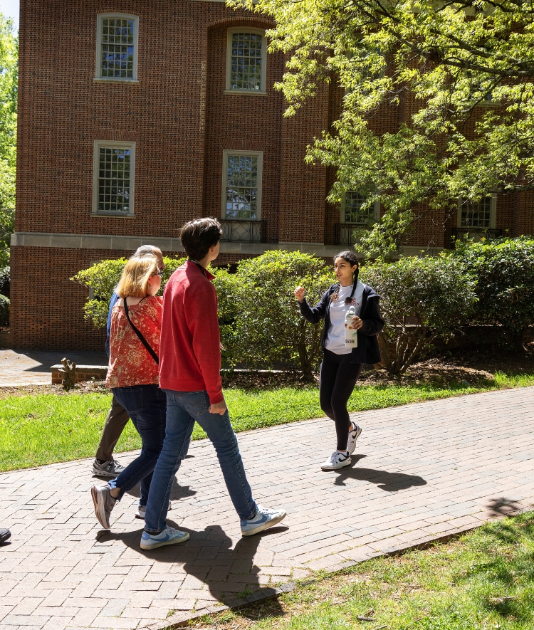 a young woman guides a family around a college campus