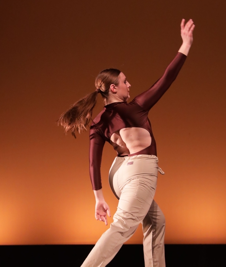 a young woman dances in a brown leotard and khaki pants