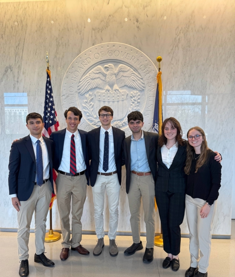 a group of six young people standing in front of the federal reserve building