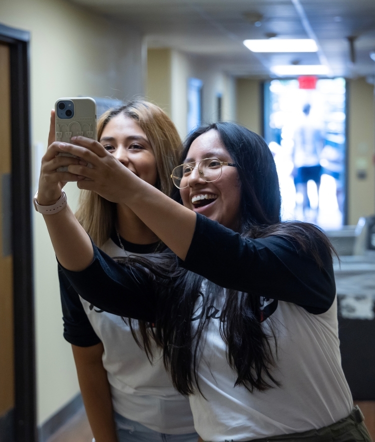 Two young women take a selfie in their dorm