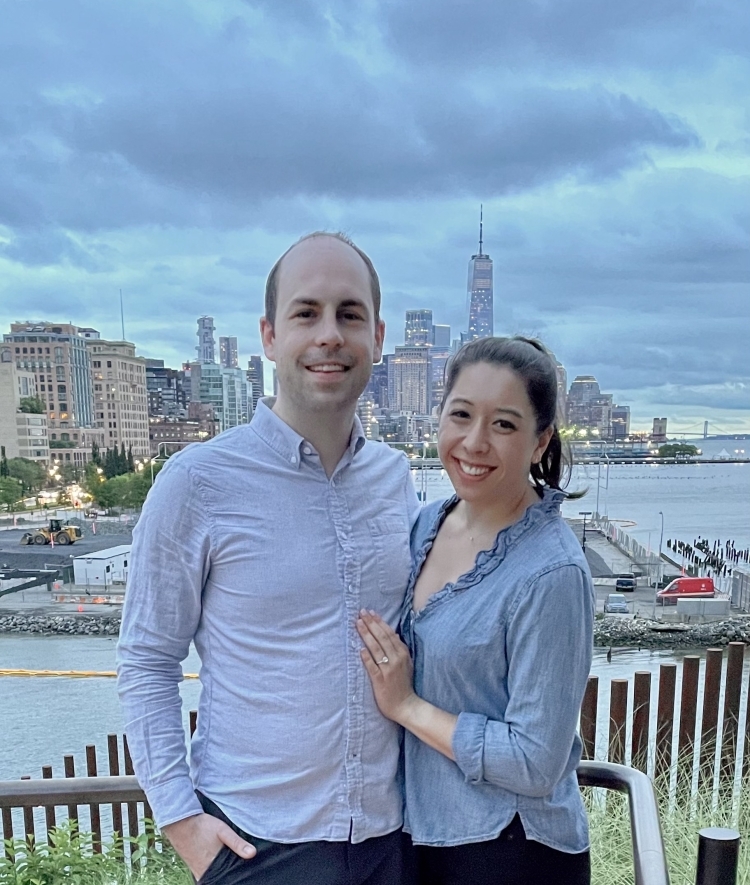 a young couple standing together in front of NYC skyline