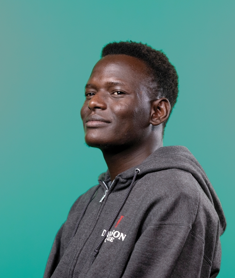 a young Black man wearing a Davidson College sweatshirt on a teal background
