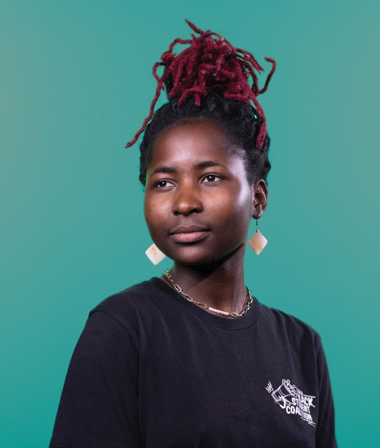 a young Black woman wearing a black tshirt on a teal background