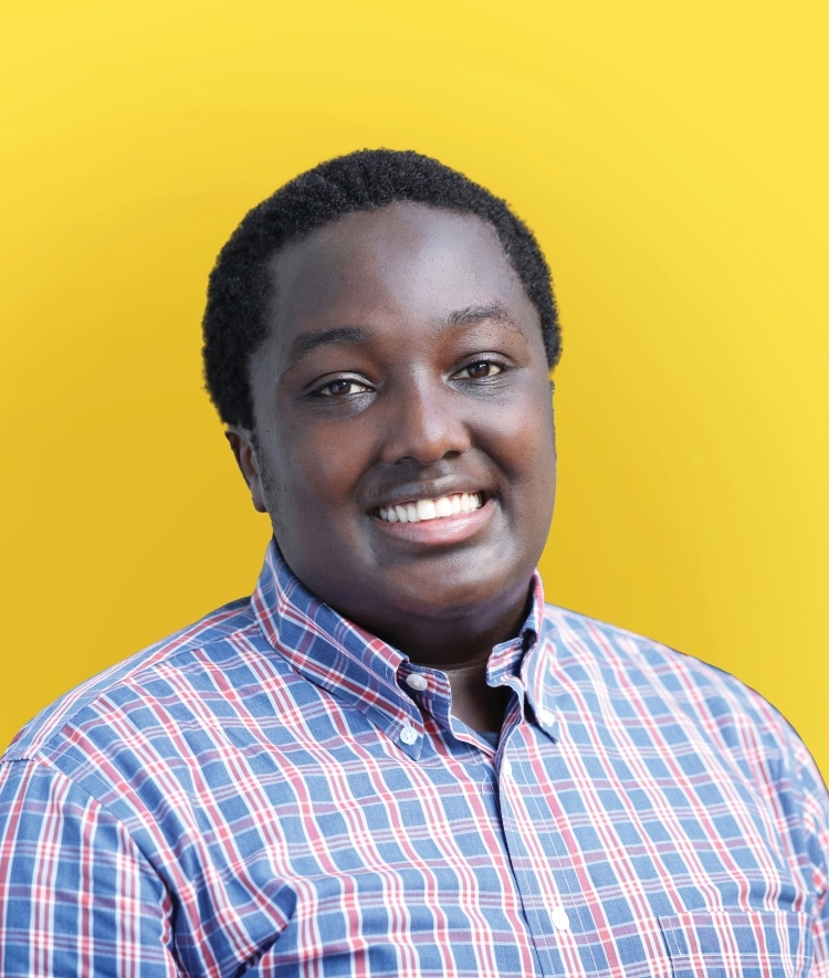 a young Black man wearing a plaid collared shirt on a yellow background