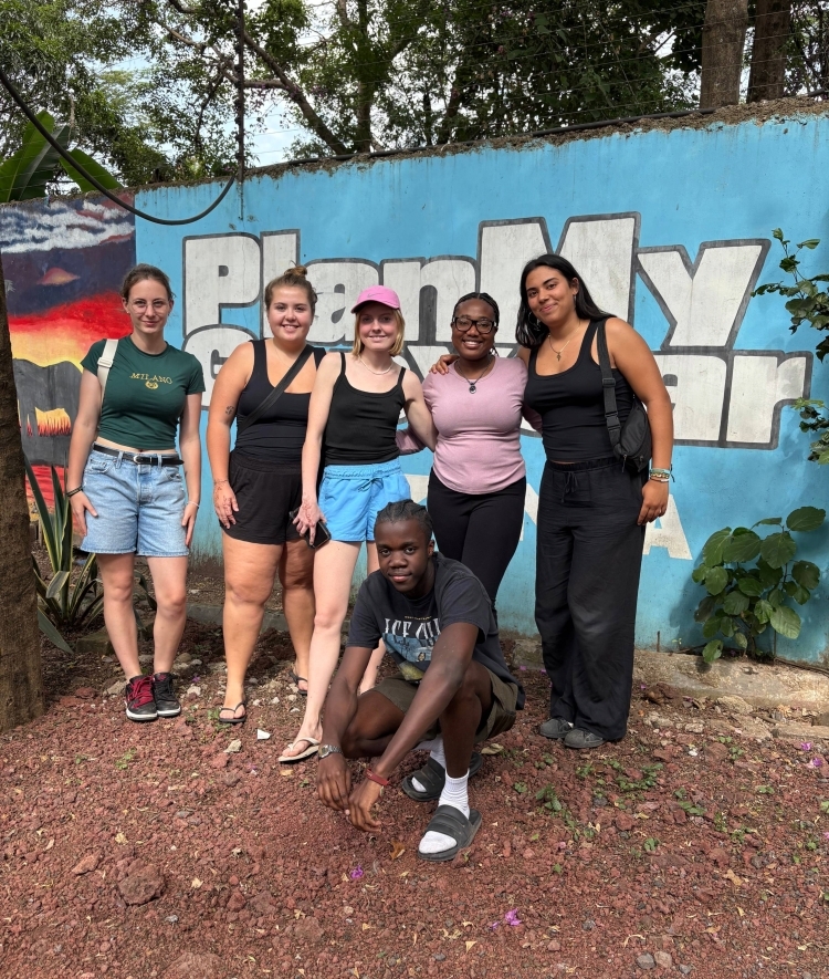 a group of students in Tanzania taking a picture in front of a wall