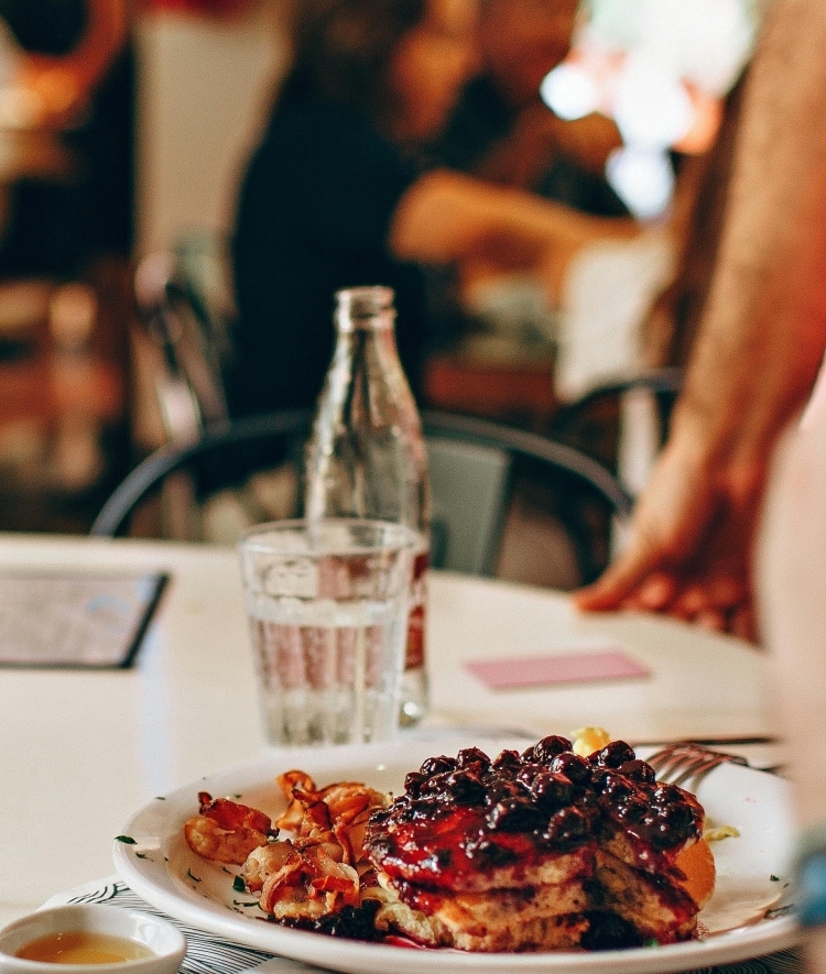a table with blueberry pancakes and bacon