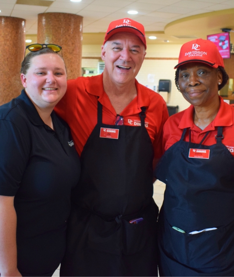 dining services workers wearing red shirts and black aprons in a dining hall