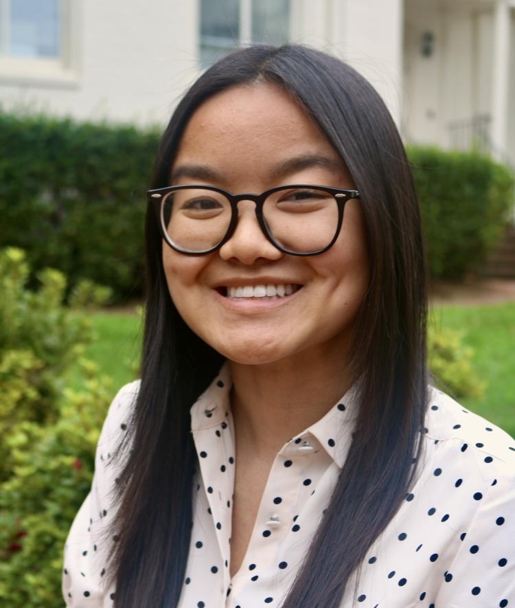 a young woman with long dark hair wearing glasses and polka dotted shirt