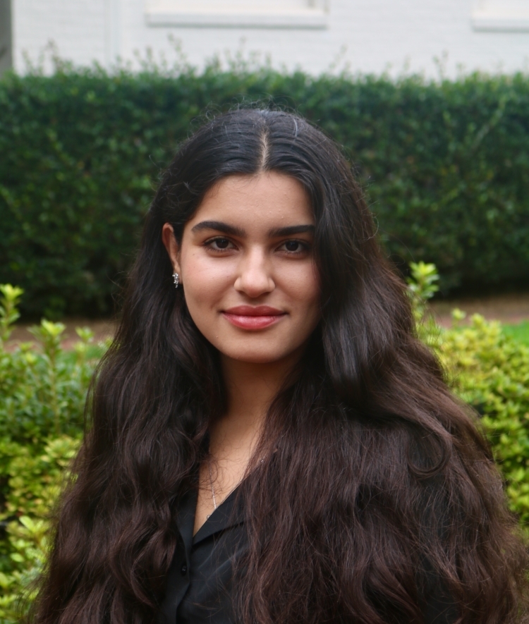 a young woman with long dark hair smiling outside