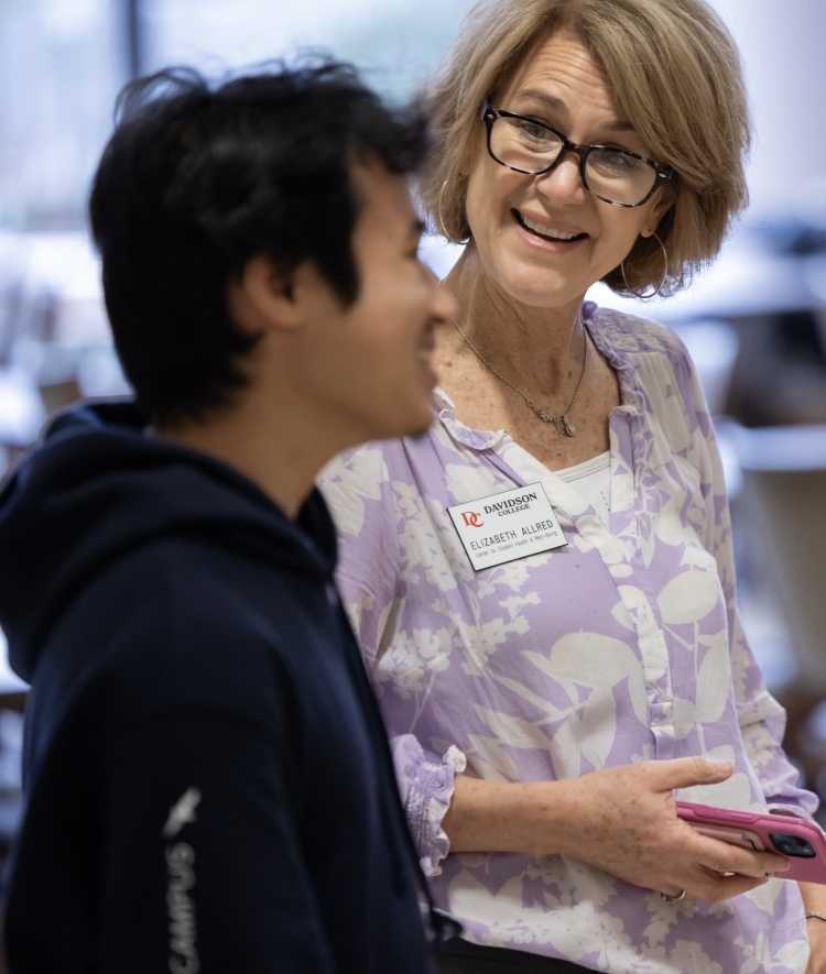 a young man talks to an older woman in a dining hall