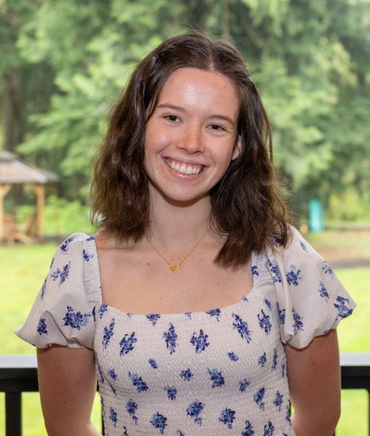 a young woman with curly brown hair wearing a white and blue top