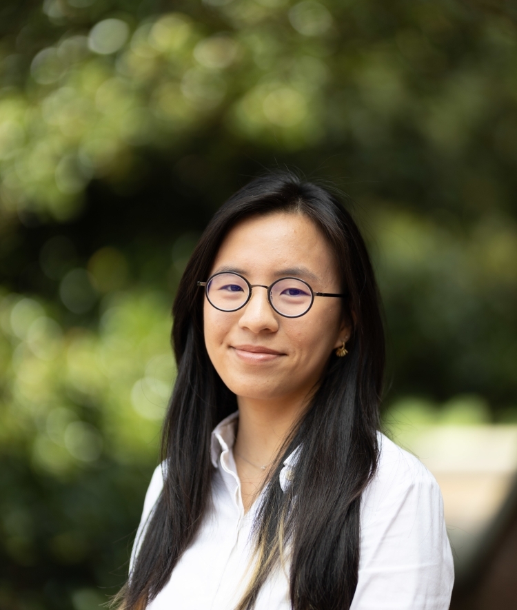 a young woman with glasses wearing a collared white shirt with long dark hair