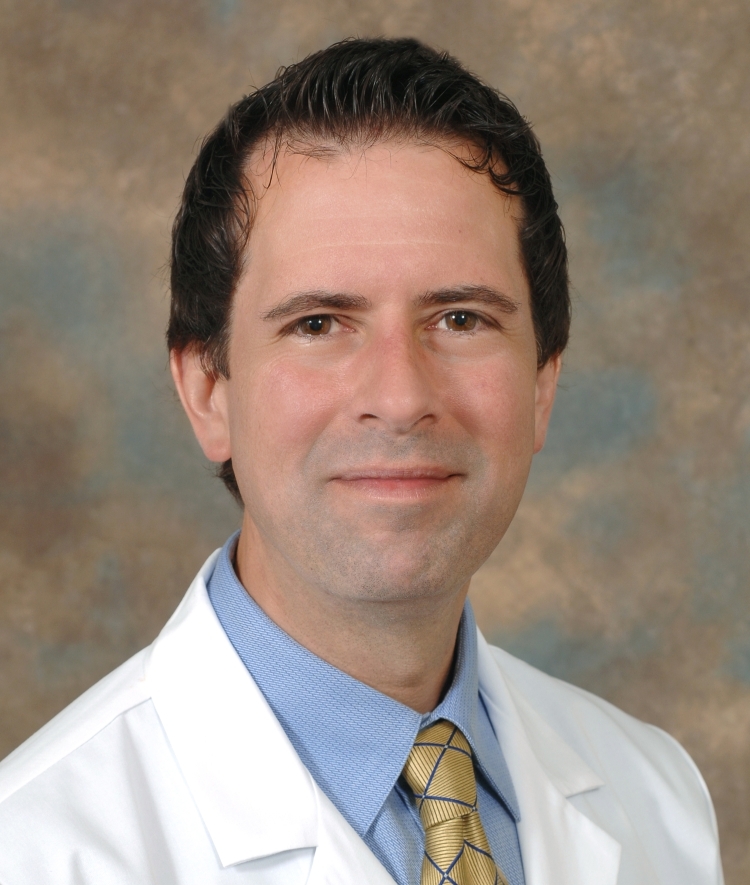 a young man with dark hair wearing a doctor's coat