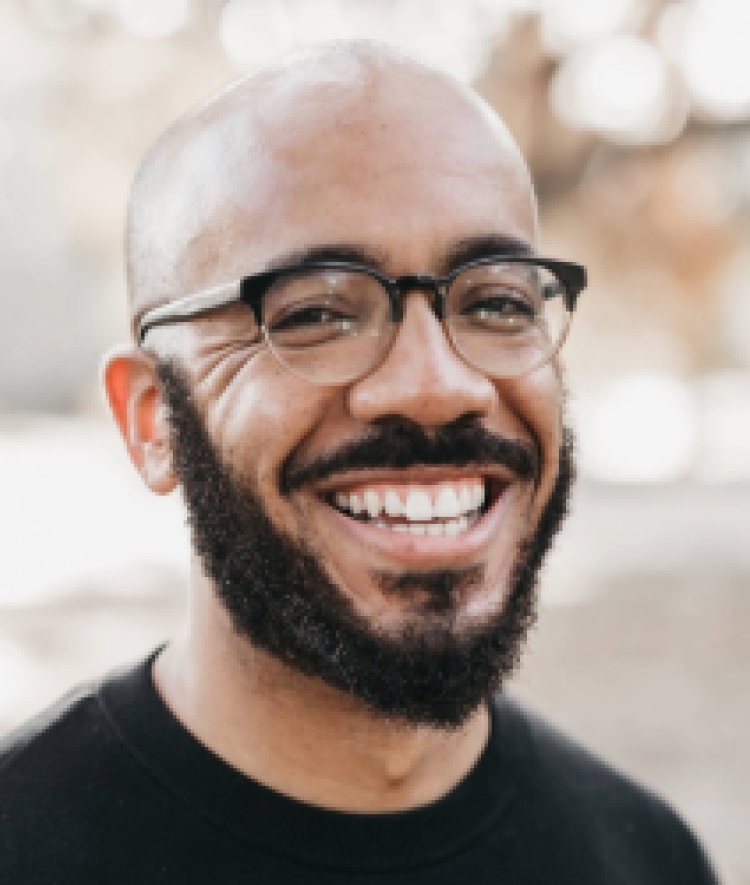a man with glasses and facial hair wearing a black top