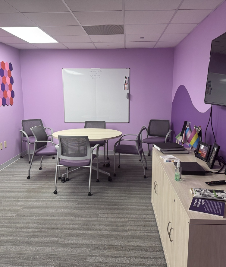 a purple painted room with a circular table and chairs as well as a tv and console