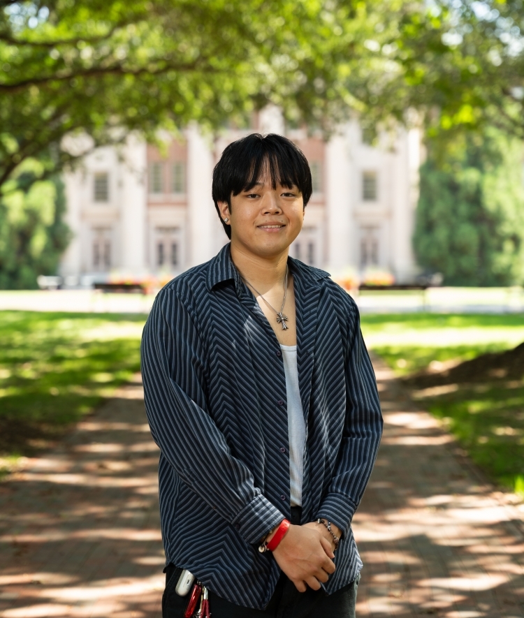 a young man smiles on a college campus