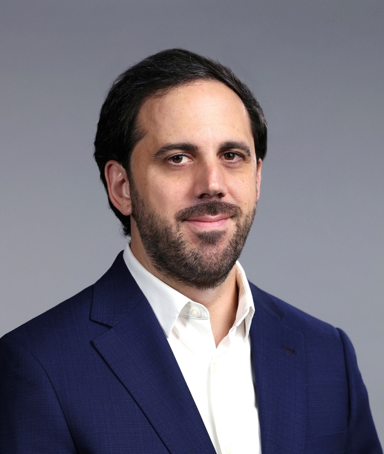 a man with facial hair and short brown hair wearing a collared white shirt and blue blazer