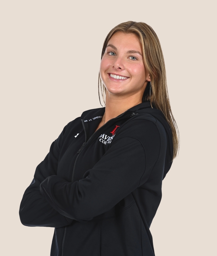 a young woman with blonde hair smiling with her arms crossed wearing a black athletic sweatshirt