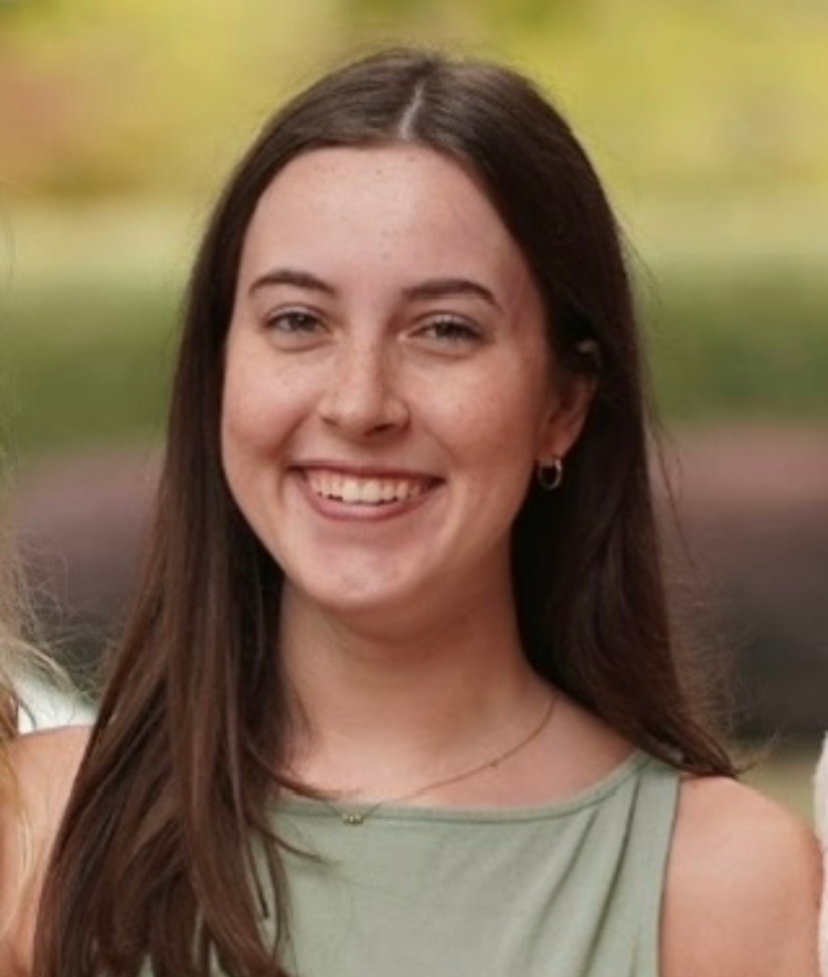 a young woman with long brown hair wearing a green tank top and smiling